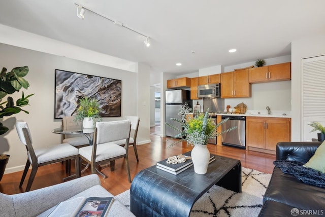 living area with recessed lighting, baseboards, rail lighting, and light wood finished floors