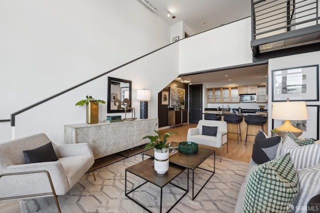 living room with light wood-type flooring and a towering ceiling