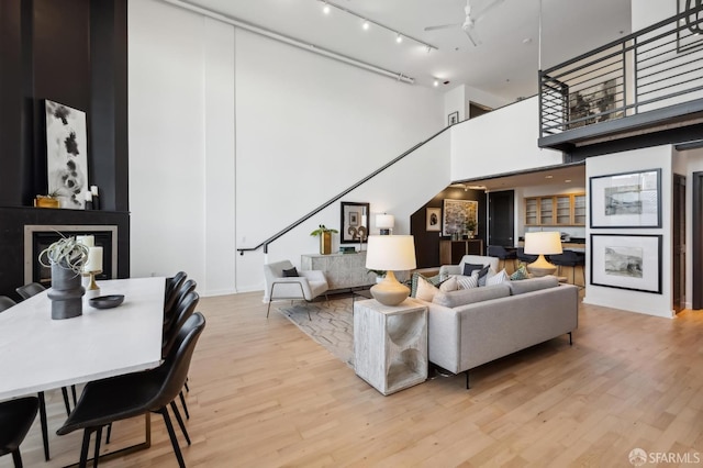 living room featuring ceiling fan, light hardwood / wood-style floors, and a high ceiling