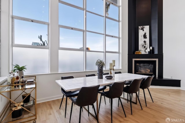 dining space with a large fireplace and light wood-type flooring