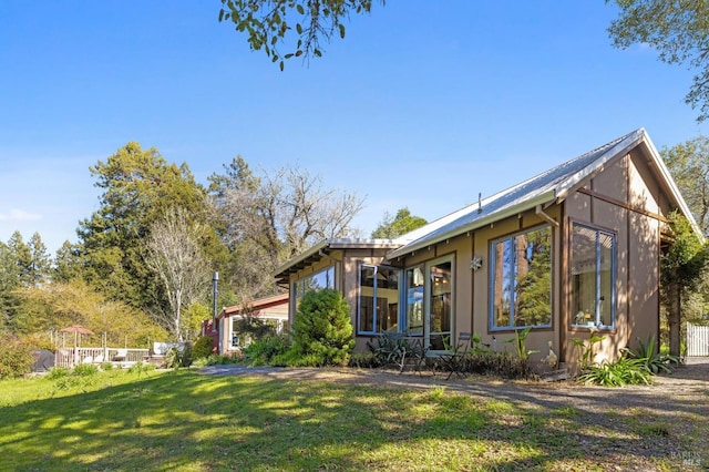 exterior space featuring a front yard, stucco siding, and a sunroom