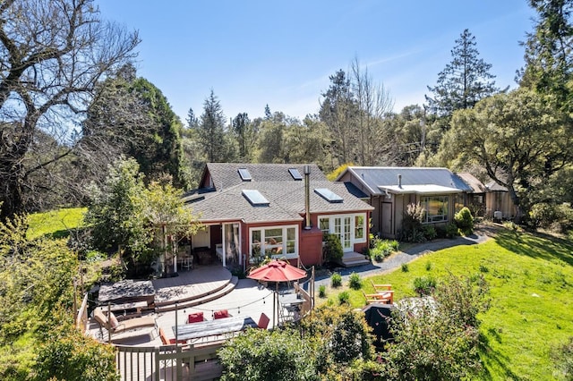 rear view of house featuring roof with shingles, french doors, a patio area, entry steps, and a lawn