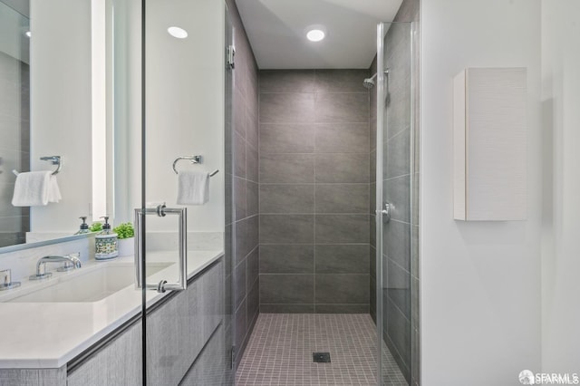 bathroom with tiled shower, vanity, and tile patterned flooring