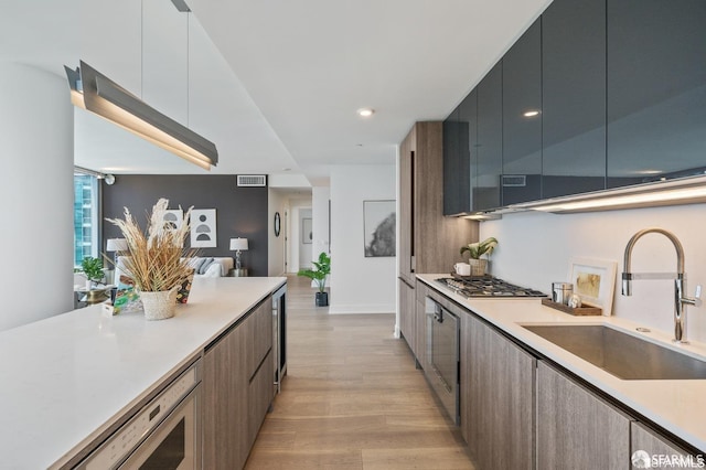 kitchen featuring stainless steel appliances, wine cooler, light hardwood / wood-style floors, and sink