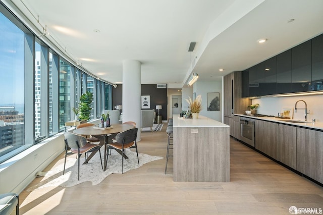 kitchen featuring light wood-type flooring, a kitchen island, sink, and a kitchen breakfast bar