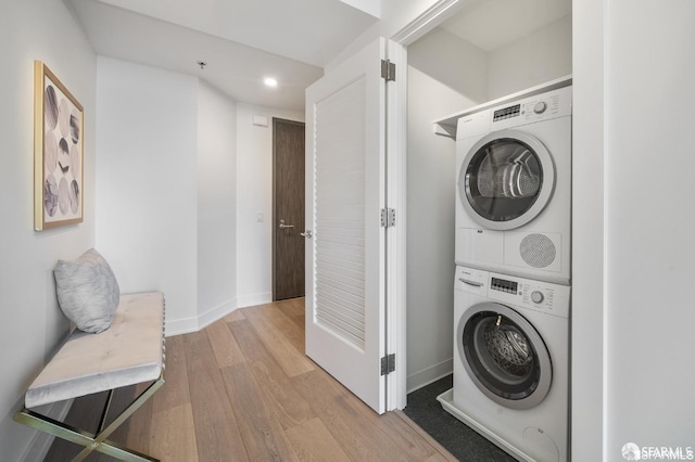 laundry room with stacked washer and clothes dryer and light wood-type flooring