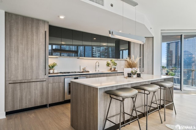 kitchen with pendant lighting, wine cooler, light wood-type flooring, and a kitchen island