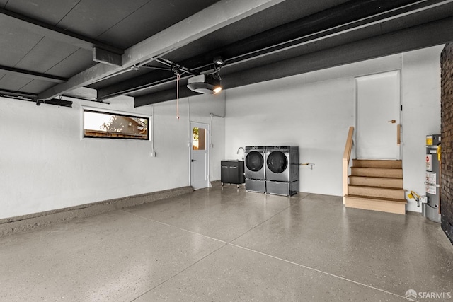 garage with a garage door opener, gas water heater, and separate washer and dryer