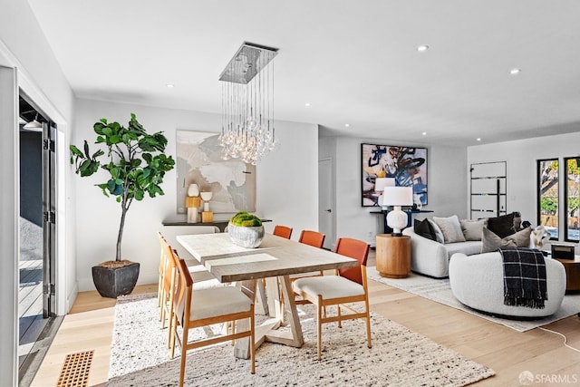 dining space with an inviting chandelier and light hardwood / wood-style flooring