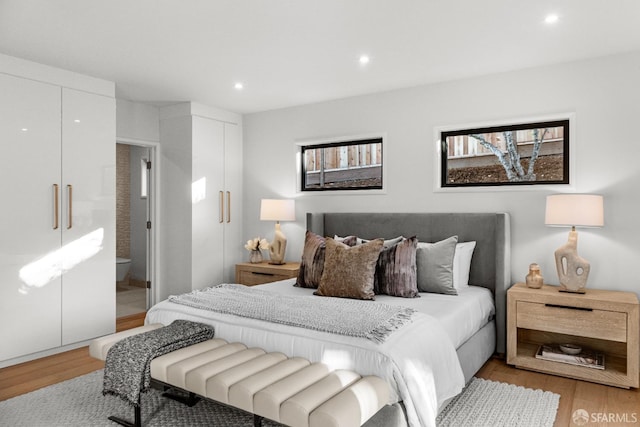 bedroom with ensuite bathroom and light hardwood / wood-style flooring