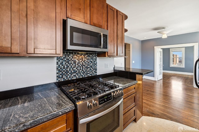 1375 Sacramento St, San Francisco, CA 94109 - kitchen with appliances with stainless steel finishes, dark countertops, brown cabinets, and decorative backsplash