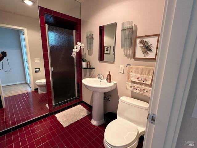 bathroom with tile patterned flooring, sink, an enclosed shower, and toilet