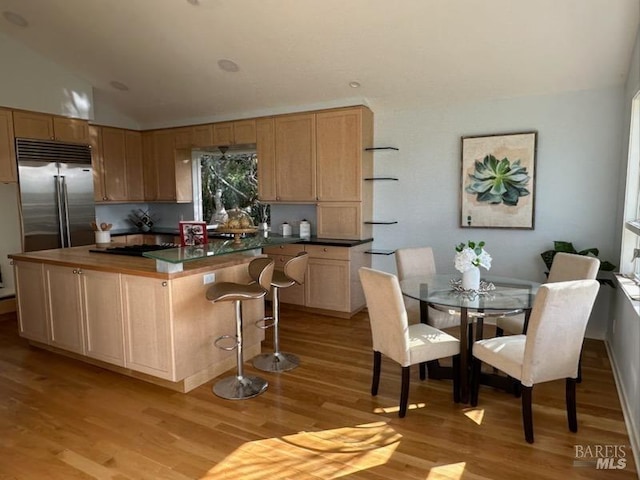 kitchen featuring lofted ceiling, light brown cabinetry, light hardwood / wood-style flooring, built in fridge, and a kitchen island