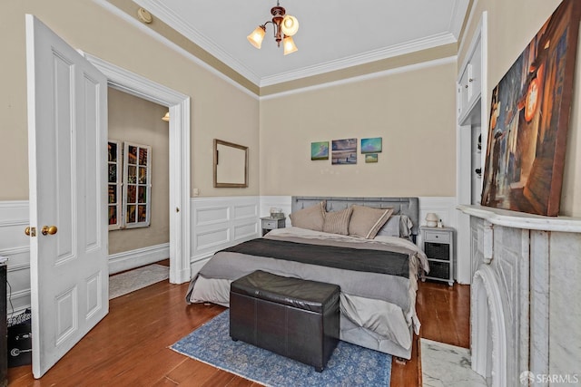 bedroom featuring a notable chandelier, wainscoting, wood finished floors, and crown molding