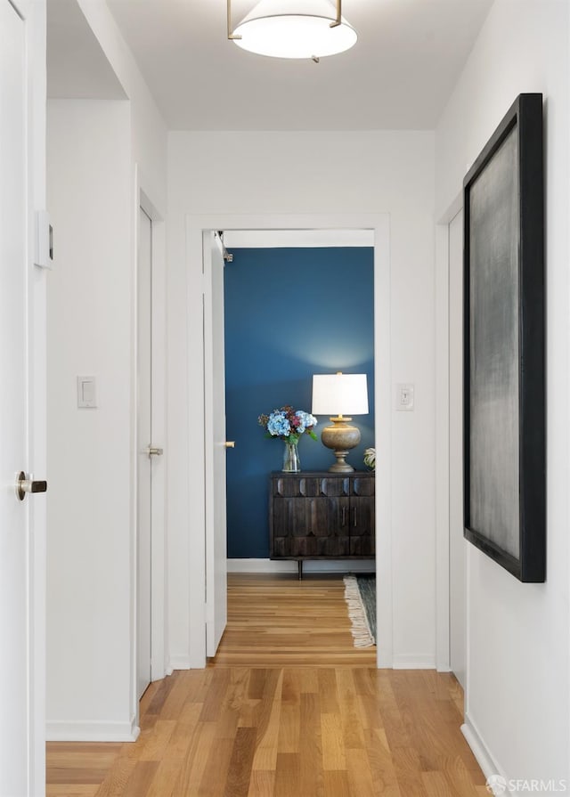 hall featuring light wood-type flooring and baseboards