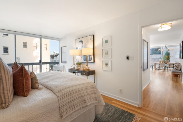 bedroom with baseboards, light wood finished floors, and an inviting chandelier