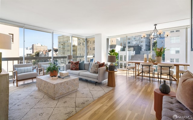 living room with a city view, visible vents, floor to ceiling windows, light wood finished floors, and an inviting chandelier