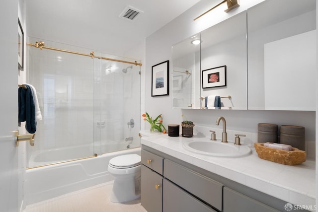 bathroom featuring enclosed tub / shower combo, visible vents, vanity, and toilet