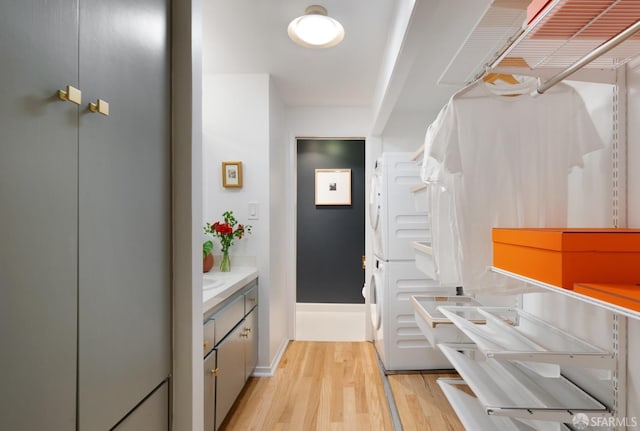 interior space with vanity, stacked washer / dryer, and wood finished floors