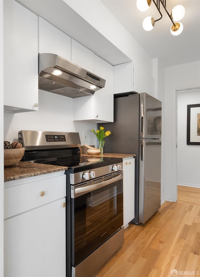 kitchen with light wood finished floors, appliances with stainless steel finishes, white cabinetry, dark stone countertops, and under cabinet range hood