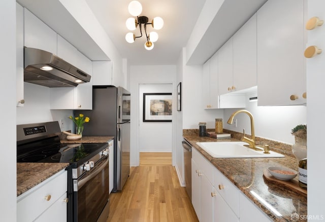 kitchen featuring white cabinets, appliances with stainless steel finishes, light wood-type flooring, under cabinet range hood, and a sink