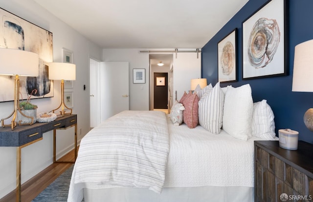 bedroom with a barn door and wood finished floors