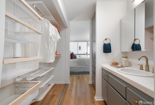 bathroom featuring ensuite bath, wood finished floors, vanity, and baseboards