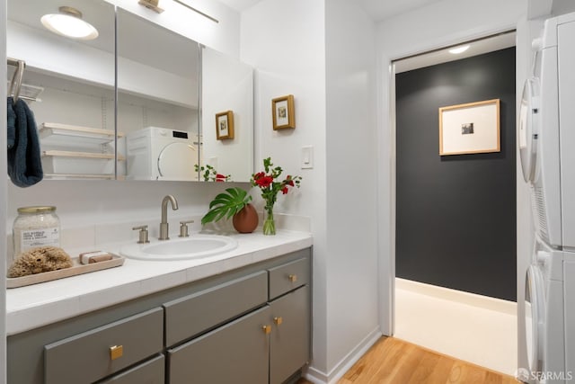 bathroom featuring stacked washer / drying machine, vanity, and wood finished floors