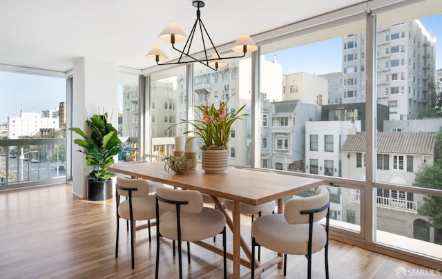 dining area with a view of city, a notable chandelier, expansive windows, and wood finished floors