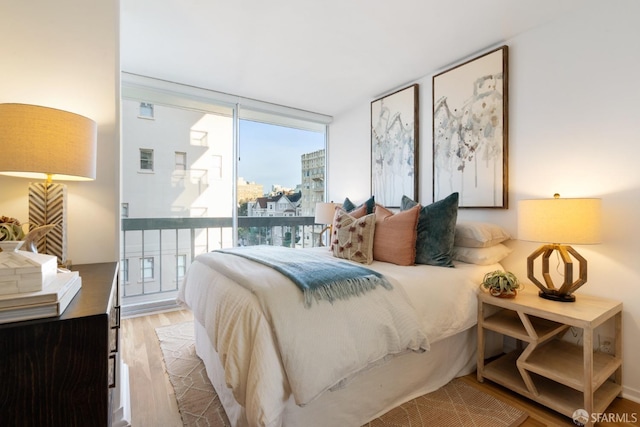 bedroom with a wall of windows and wood finished floors