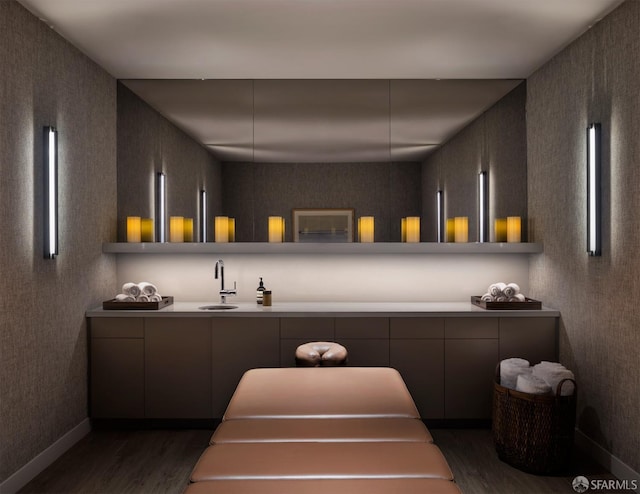 bar featuring dark wood-type flooring, a sink, and baseboards