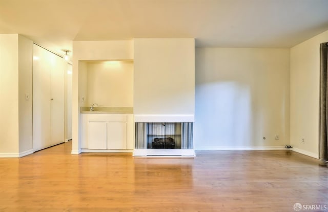 unfurnished living room featuring light hardwood / wood-style floors and sink