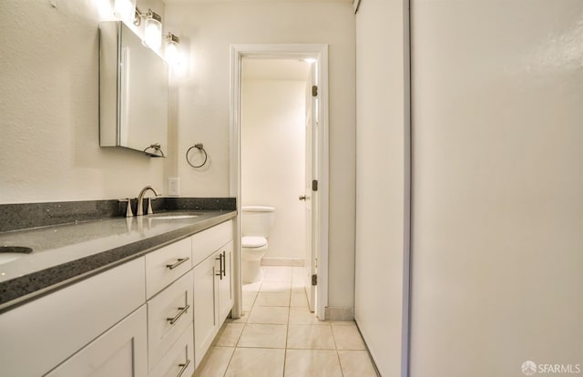 bathroom with toilet, vanity, and tile patterned floors