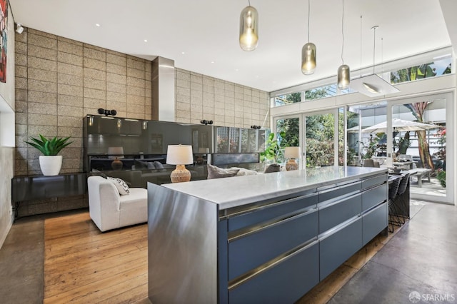 kitchen featuring hanging light fixtures, tile walls, a kitchen island, blue cabinetry, and concrete flooring