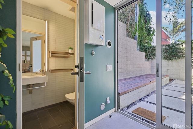 bathroom with sink, tile walls, and toilet