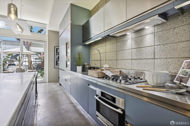 kitchen featuring concrete flooring, decorative light fixtures, stainless steel appliances, and tasteful backsplash