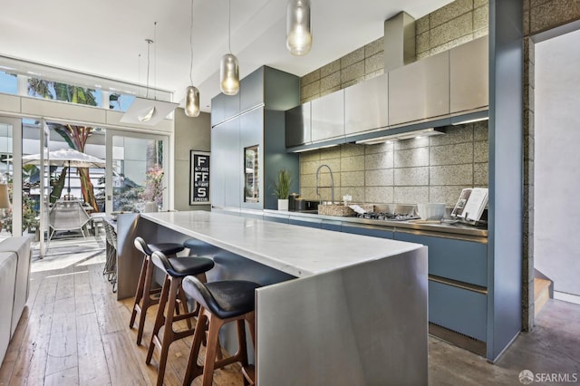 kitchen with pendant lighting, sink, dark hardwood / wood-style floors, a kitchen bar, and decorative backsplash