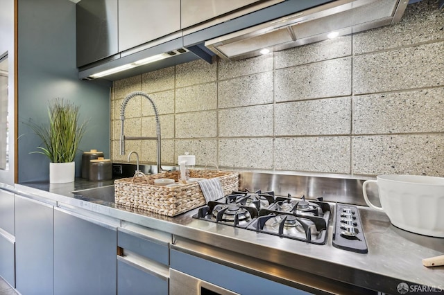 kitchen with backsplash, blue cabinetry, and stainless steel counters