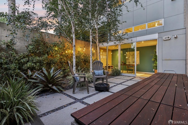 deck at dusk featuring an outdoor fire pit and a patio area