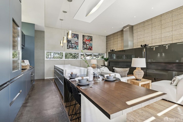 kitchen featuring a towering ceiling, a skylight, a large island, and hanging light fixtures