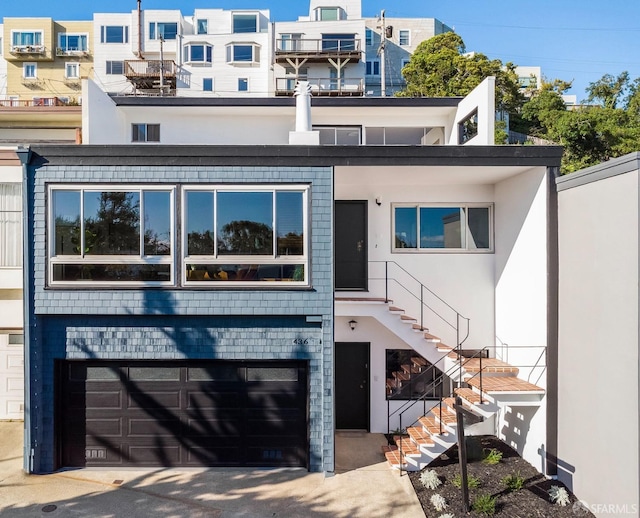 view of property featuring a garage, stairway, and stucco siding