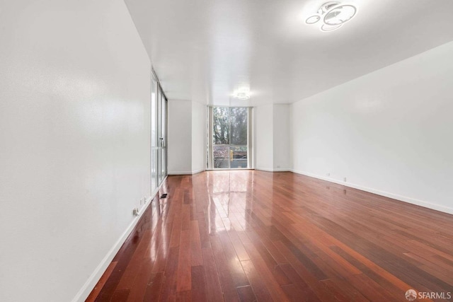 empty room featuring a wall of windows and dark hardwood / wood-style floors