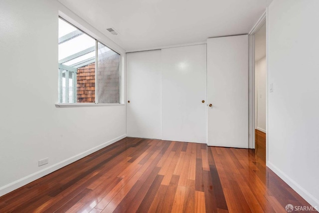 unfurnished bedroom with dark hardwood / wood-style flooring and a closet