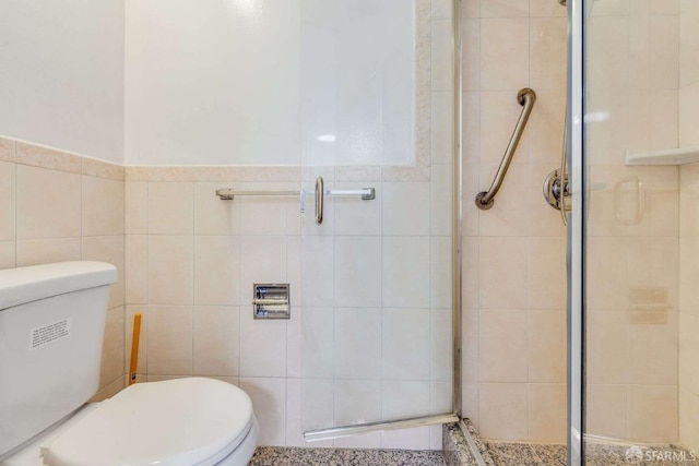 bathroom featuring tile walls, an enclosed shower, and toilet