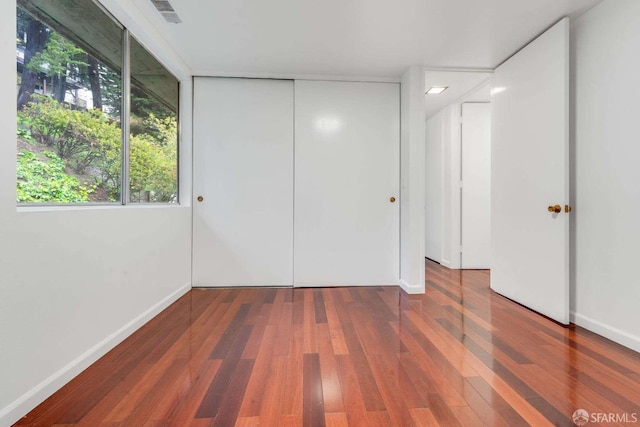 unfurnished bedroom featuring dark wood-type flooring and a closet