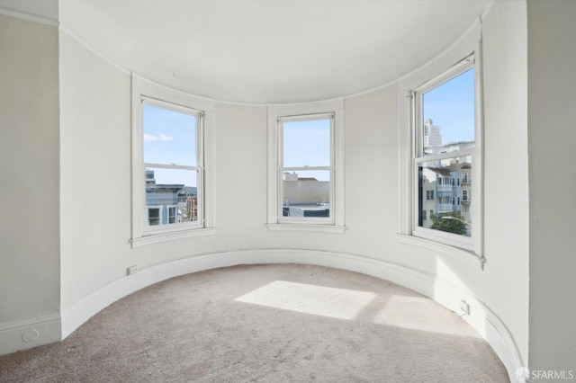 carpeted spare room with plenty of natural light and baseboards