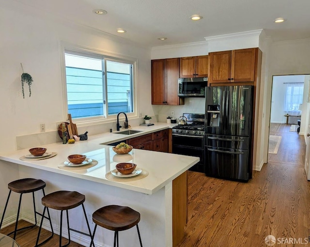 192 Ridgeway Ave, Oakland, CA 94611 - kitchen with black appliances, a peninsula, brown cabinets, a breakfast bar, and ornamental molding