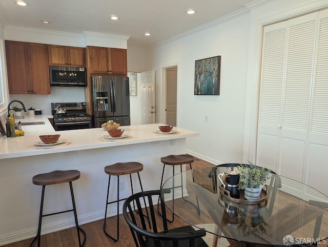 192 Ridgeway Ave, Oakland, CA 94611 - kitchen with stainless steel appliances, a peninsula, dark wood-style floors, a breakfast bar area, and ornamental molding