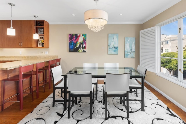 dining space with a healthy amount of sunlight, crown molding, and wood finished floors