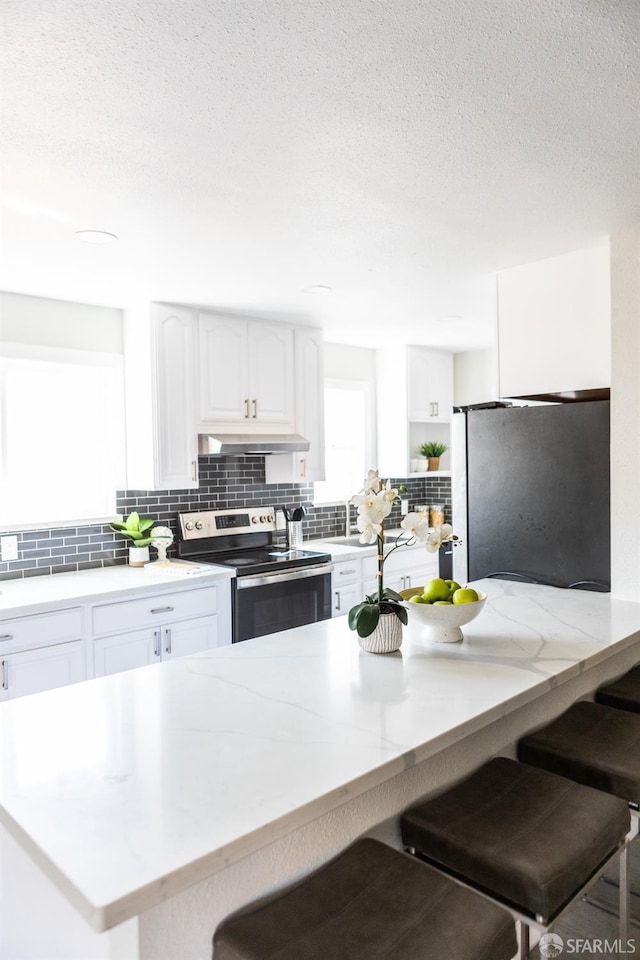 28290 Thackeray Ave, Hayward, CA 94544 - kitchen with stainless steel appliances, backsplash, under cabinet range hood, a breakfast bar, and a textured ceiling